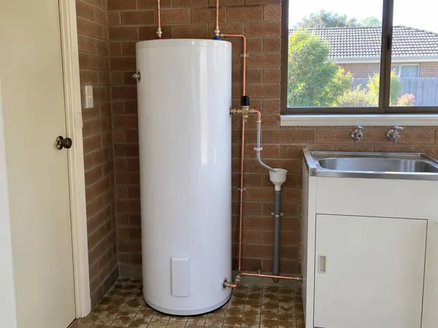 White hot water cylinder beside laundry sink on a brick wall in Castle Hill